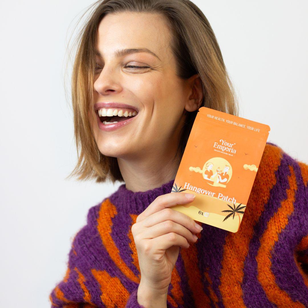 Woman smiling while holding a detox patch, promoting wellness and recovery.