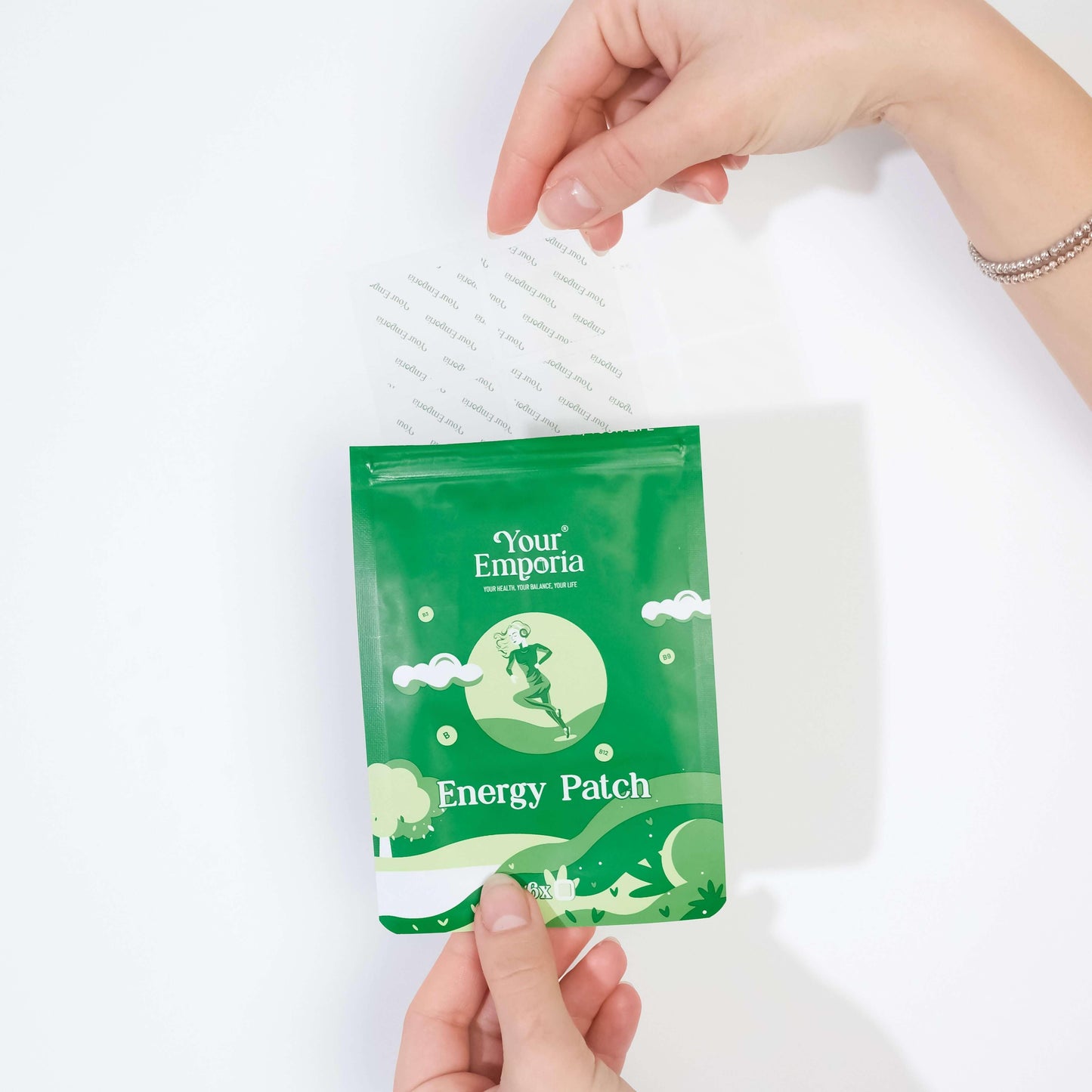 Hands holding an opened package of Energy Patch by Your Emporia, ready for use to boost vitality and performance.